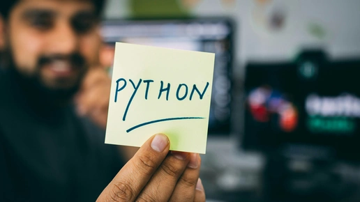 A cluttered desk with a laptop screen showing Python code and a cup of cold tea.